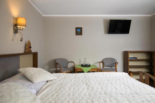 a bedroom with a white bed and a table and chairs at Hotel STARÝ MLÝN in Jeseník
