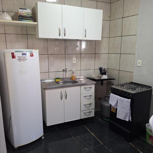 a kitchen with a white refrigerator and a sink at Pousada da Celma in Fortaleza