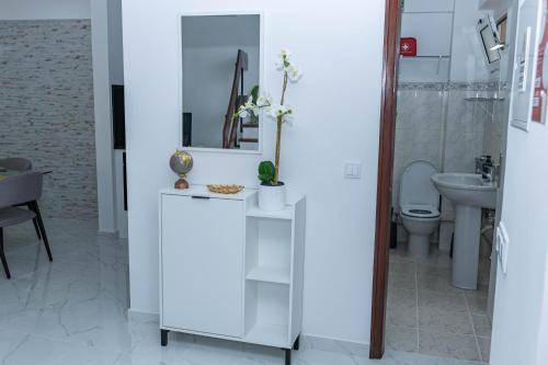 a white bathroom with a toilet and a sink at MCM Matur Flats 2, 11 Duplex in Santa Cruz