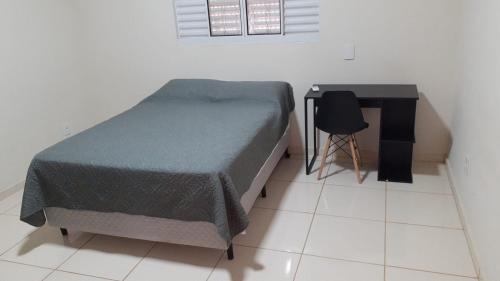 a bedroom with a bed and a desk and a chair at Pousada Am confort turiuba ltda in Turiúba