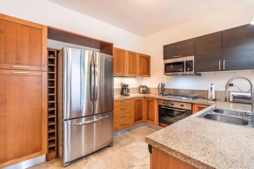 a kitchen with wooden cabinets and a stainless steel refrigerator at Samana Ocean View Villa in Los Grini