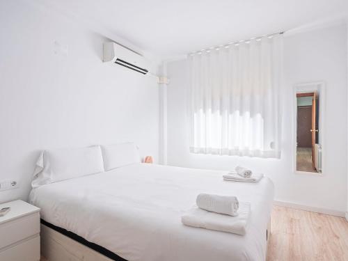 ein weißes Schlafzimmer mit einem großen Bett mit Handtüchern darauf in der Unterkunft Playa, Port Fórum y BCN centro a 10 min - Apartamento con Vistas in Sant Adria de Besos