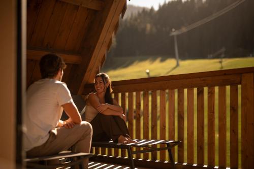 a man and woman sitting on the porch of a cabin at ADEA Lifestyle Suites Fieberbrunn in Fieberbrunn