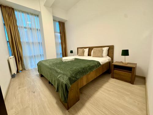 a bedroom with a large bed with a green blanket at Kim Urban Suites in Cluj-Napoca