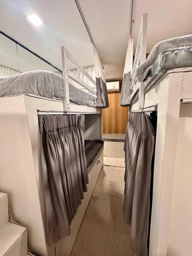 a small room with two bunk beds and curtains at Blu Cabin Ari Stylish Gay Poshtel in Bangkok