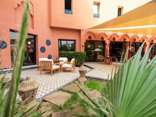 a patio with a table and chairs in front of a building at Ibis Marrakech Centre Gare in Marrakech