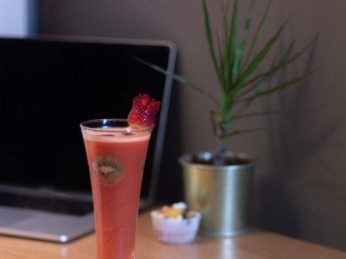 a drink with a strawberry on a desk with a laptop at Ibis Marrakech Centre Gare in Marrakech