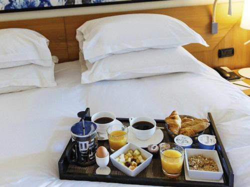 a tray with breakfast foods on a bed at Sofitel Biarritz Le Miramar Thalassa in Biarritz