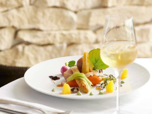 a white plate of food and a glass of wine at Sofitel Biarritz Le Miramar Thalassa in Biarritz