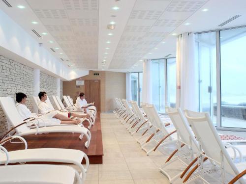 a group of people sitting in a waiting room with white chairs at Sofitel Biarritz Le Miramar Thalassa in Biarritz