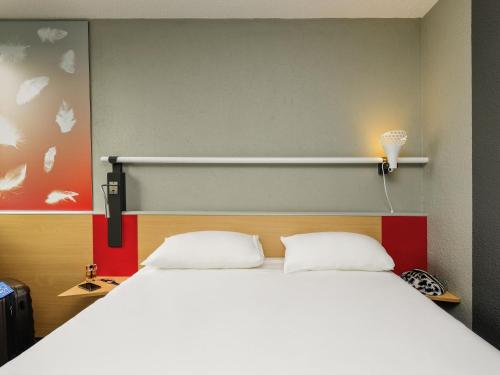 a bedroom with a large white bed with a headboard at ibis Longwy Mexy in Mexy