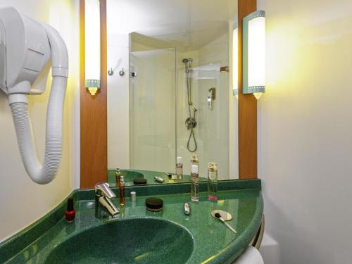 a bathroom with a green sink and a shower at ibis Longwy Mexy in Mexy