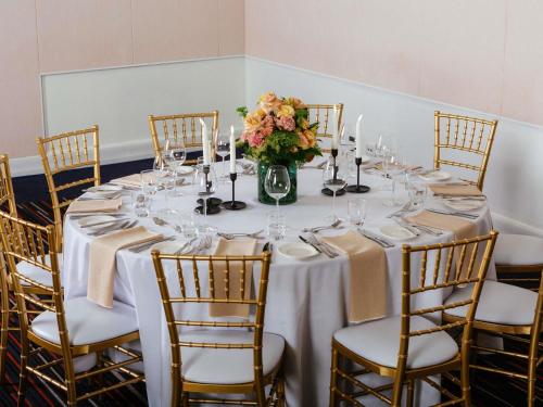 a long table with chairs and a vase of flowers at Novotel Melbourne Glen Waverley in Glen Waverley
