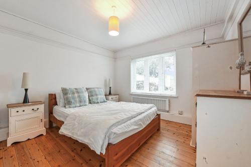 a white bedroom with a bed and a window at Saltwater, East Wittering in East Wittering
