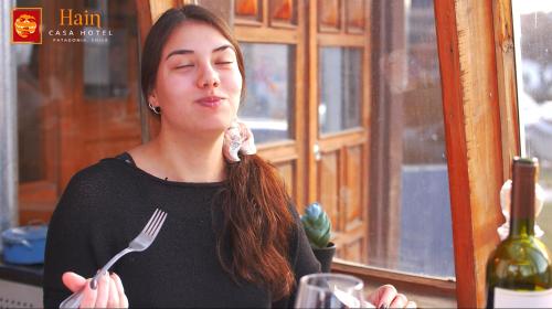 a woman holding a fork and a bottle of wine at Hain Casa Hotel in Punta Arenas