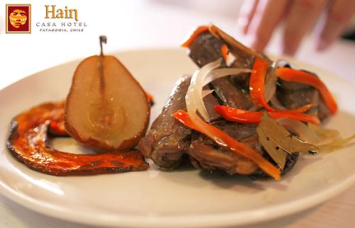 a white plate of food with meat and vegetables at Hain Casa Hotel in Punta Arenas