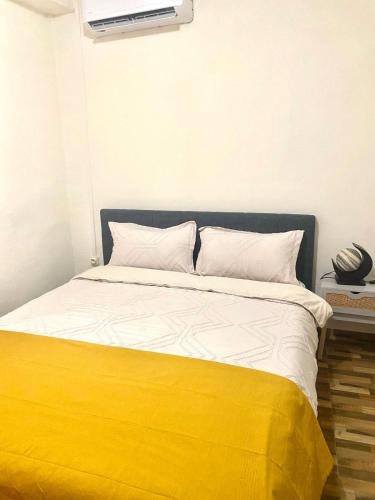 a bed with a yellow and white blanket on it at Charmant T2 a Mtsapere Mamoudzou in Mamoudzou