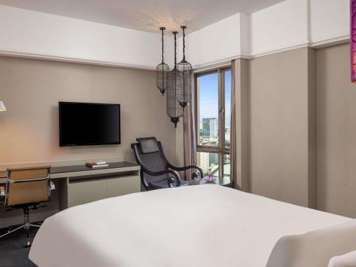 a hotel room with a bed and a desk and a tv at Sofitel Saigon Plaza in Ho Chi Minh City