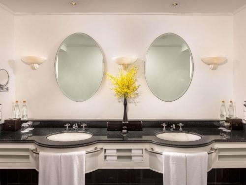 a bathroom with two sinks and two mirrors at Sofitel Saigon Plaza in Ho Chi Minh City