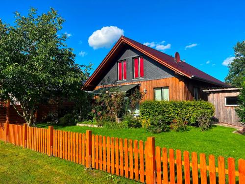 a wooden house with red windows behind a fence at Ferienhaus "Himi" in unmittelbarer Nähe des Passader Sees in Passade