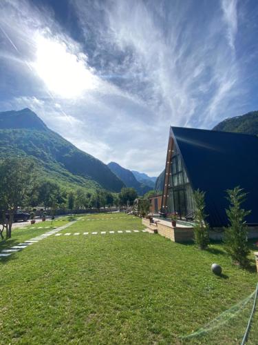 a barn with a grass field next to a building at Monark Villas in Shkodër