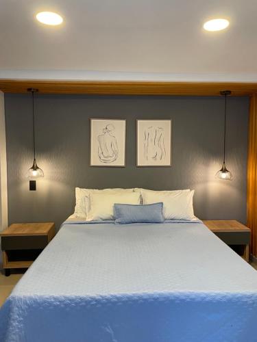 a bedroom with a blue bed with two pictures on the wall at Ivanna Jumar ApartaHotel in Medellín