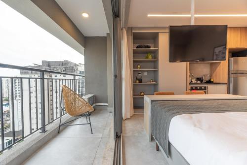 a bedroom with a bed and a balcony with a tv at Charlie Vitrali Moema in Sao Paulo