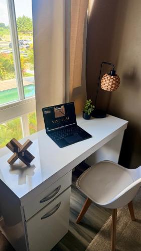 a white desk with a laptop on it next to a window at Vive Luxe Condo w Pool & 247 Security near Airport in Dabadie
