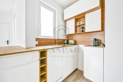 a kitchen with white cabinets and a sink at Gaspar- Passages- Comfort & proximity to Paris in Boulogne-Billancourt