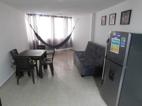 a living room with a couch and a table and a refrigerator at El Velero Apartamentos By DANP in Santa Marta