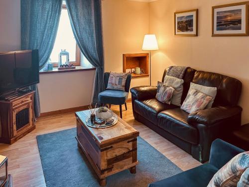 Una sala de estar con un sofá de cuero y un televisor. en Seahaven Cottage, en Portknockie