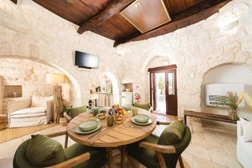 a living room with a wooden table and green chairs at Trulli Arborea in Alberobello
