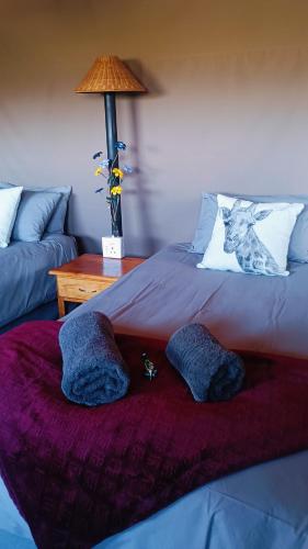 a bed with two pillows and a table with a lamp at Shamba Yetu Mountain Lodge in Maanhaarrand