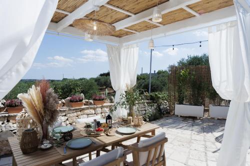 a patio with a wooden table and chairs and a tableablish at Trulli Arborea in Alberobello