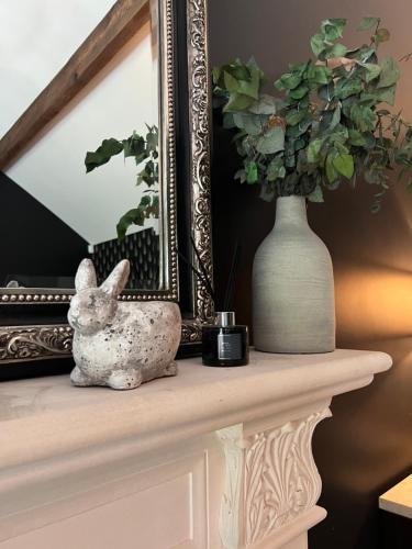 a rabbit sitting on a mantle with a mirror and a vase at Luxury Croft Templepatrick Near Airport Rabbit and Hilton hotel in Templepatrick