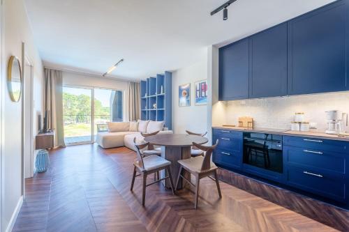 a kitchen with blue cabinets and a table and chairs at Czarna Perła Hel in Hel