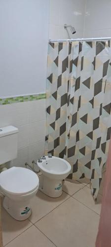 a bathroom with a toilet and a shower curtain at Complejo Los Azahares in Presidencia Roque Sáenz Peña