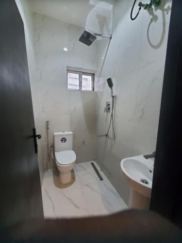 a white bathroom with a toilet and a sink at Del hotel and suites in Mama