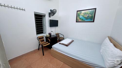 a bedroom with a bed and a table and a window at Nha Nghi Phu Quy in Phú Nặng