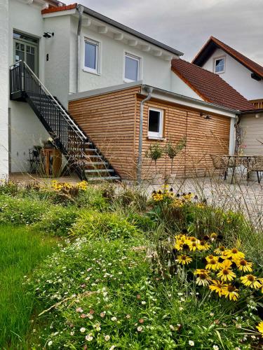 a house with a staircase and flowers in the yard at Ferienwohnung Fränkische Auszeit in Wolframs-Eschenbach