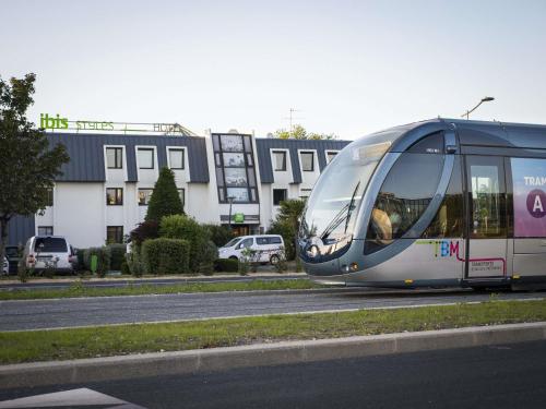 a tram driving down a street in front of a building at ibis Styles Bordeaux Aéroport in Mérignac
