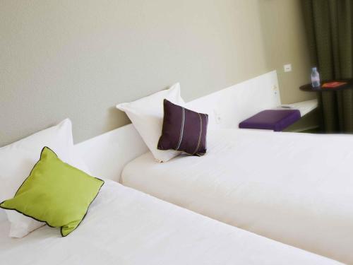 a white bed with two pillows on top of it at ibis Styles Bordeaux Aéroport in Mérignac