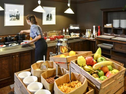 a woman standing in a kitchen preparing food at ibis Charleroi Centre Gare in Charleroi