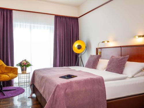 a bedroom with a large bed and a yellow chair at Mercure Hotel Bad Oeynhausen City in Bad Oeynhausen