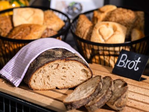 a loaf of bread on a table with baskets of bread at Mercure Hotel Bad Oeynhausen City in Bad Oeynhausen