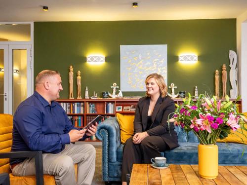 a man and woman sitting on a couch in a living room at Mercure Hotel Bad Oeynhausen City in Bad Oeynhausen