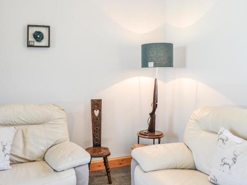 a living room with two white chairs and a lamp at West Lanegate Farmhouse in Amisfield Town