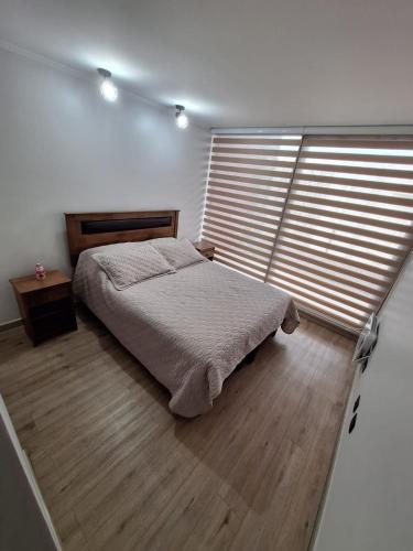 a bedroom with a bed and a large window at Departamento nuevo Pucón in Pucón