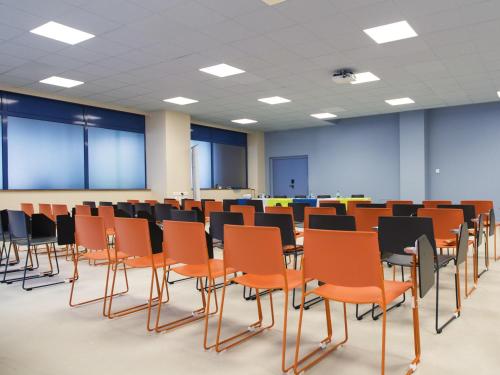 an empty room with orange chairs in a classroom at ibis Styles Toulon Centre Port in Toulon