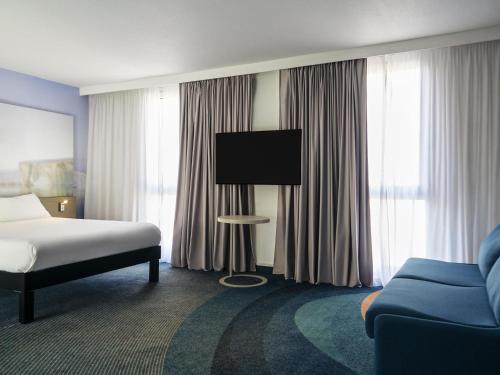 a hotel room with a bed and a tv and a couch at ibis Styles Toulon Centre Port in Toulon